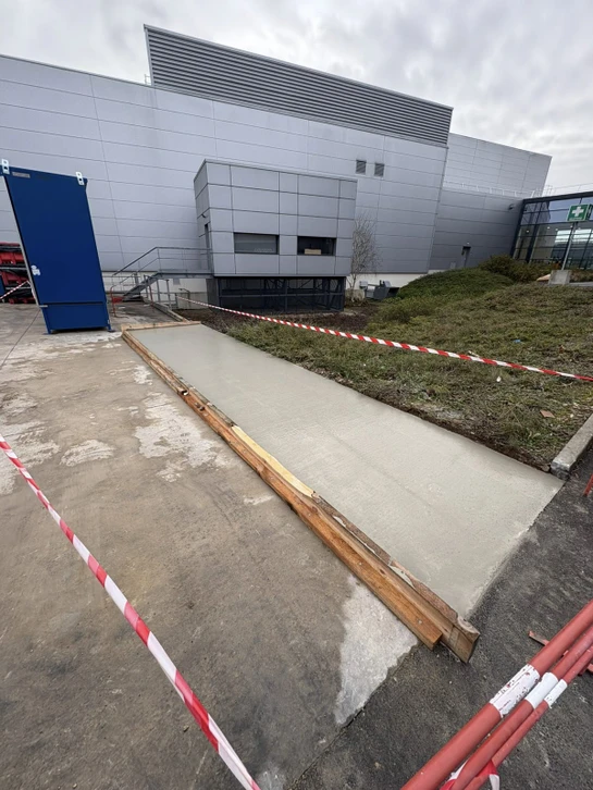 Ouvrier en combinaison bleue et casque jaune manipulant des blocs de b&eacute;ton cellulaire sur chantier de construction