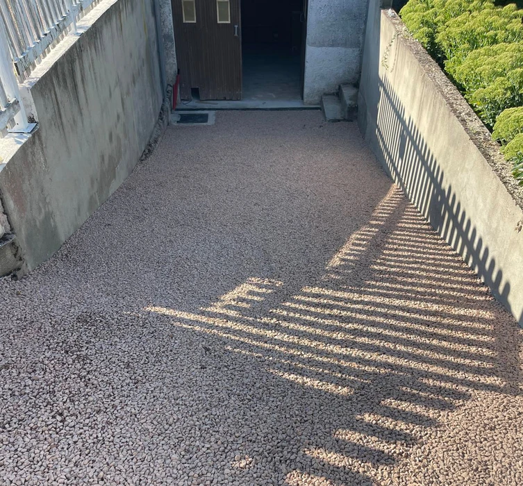 Chantier de construction extérieur avec dalle béton fraîchement coulée délimitée par coffrages bois et barrières de sécurité rouge et blanc