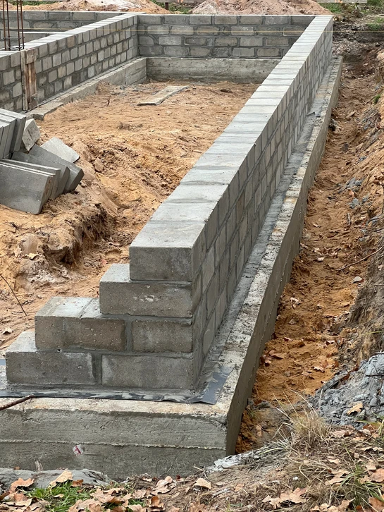 Chantier de construction extérieur avec ouvriers manipulant des matériaux de maçonnerie