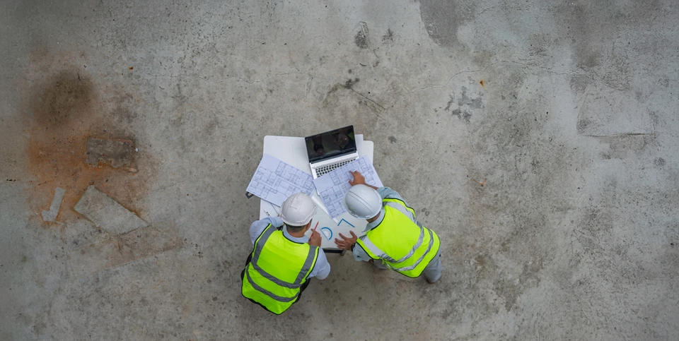 Mur extérieur en béton fissuré avec importantes lézardes verticales, surface dégradée présentant traces d'humidité et effritement