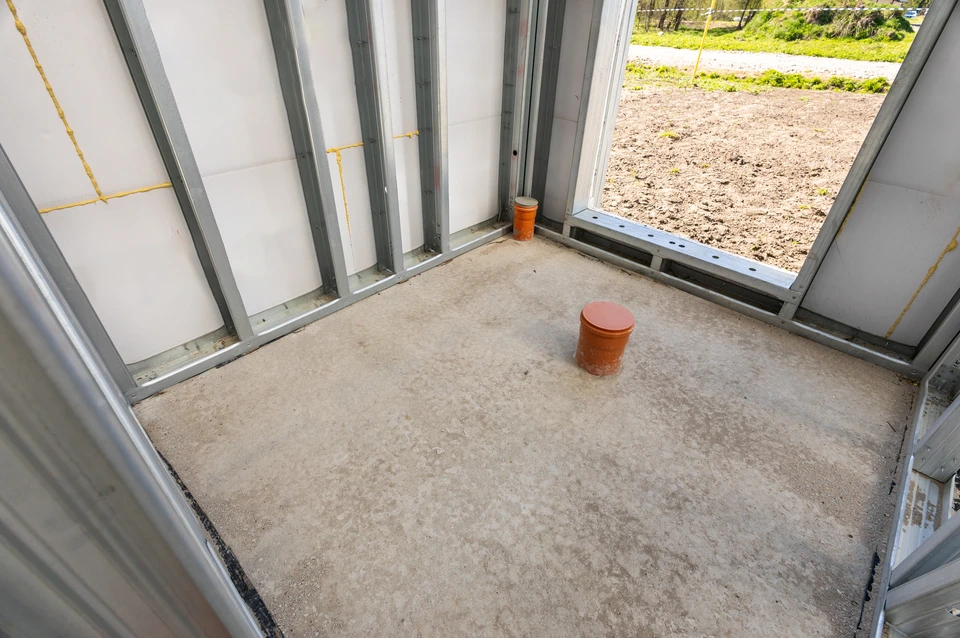 Ouvrier en b&acirc;timent construisant un mur en parpaings &agrave; l'ext&eacute;rieur, utilisant un niveau &agrave; bulle pour v&eacute;rifier l'alignement